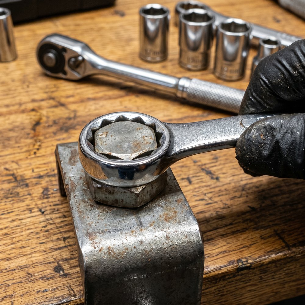 A 12-point box-end wrench seated fully over a hex bolt head, the six corners of the bolt nesting into the twelve points of the ring.